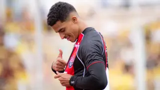 Renê souza apontando para o escudo do Vitória na camisa