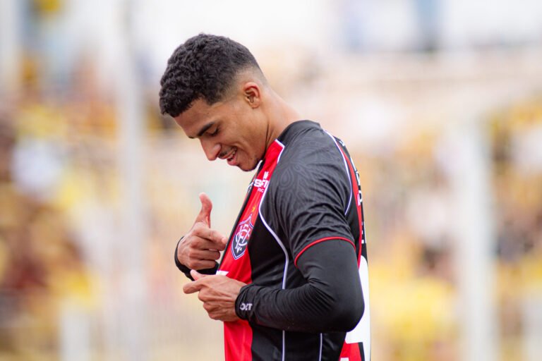 Renê souza apontando para o escudo do Vitória na camisa
