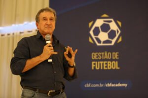 Parreira fala ao microfone durante palestra do curso Gestão de Futebol da CBF Academy, módulo realizado em Teresópolis, com o painel "Gestão de Futebol" da CBF Academy ao fundo.