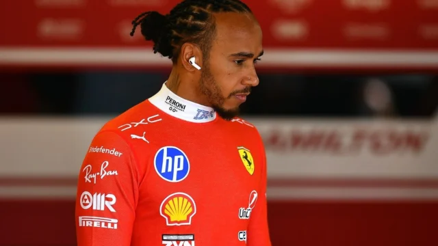 Lewis Hamilton em entrevista com microfones à sua frente, sorrindo e gesticulando