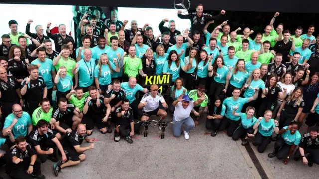 Carro da equipe Mercedes-AMG Petronas F1 Team em alta velocidade na pista, com o logo da Fórmula 1 ao fundo.
