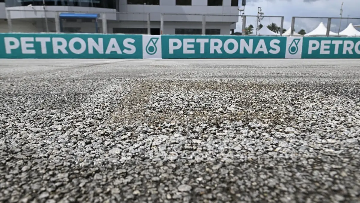 Moto de MotoGP em ação no circuito de Sepang, Malásia, com o asfalto apresentando sinais de desgaste