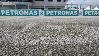 Moto de MotoGP em ação no circuito de Sepang, Malásia, com o asfalto apresentando sinais de desgaste