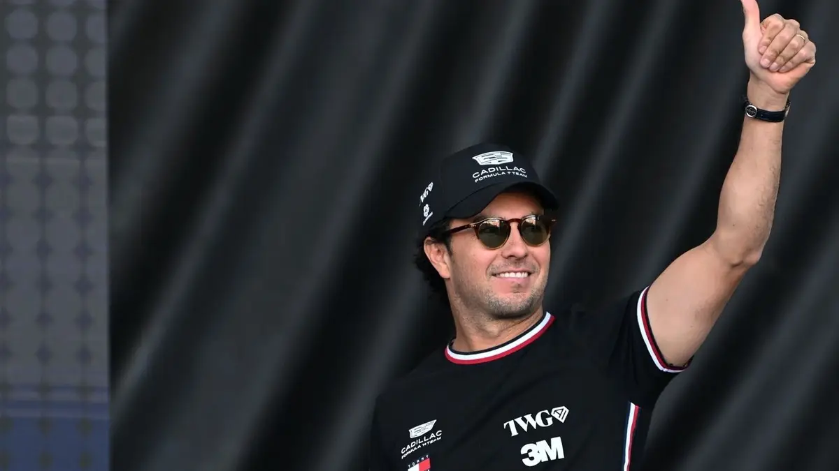 Sergio Pérez sorri ao lado de um carro de Fórmula 1 da equipe Cadillac