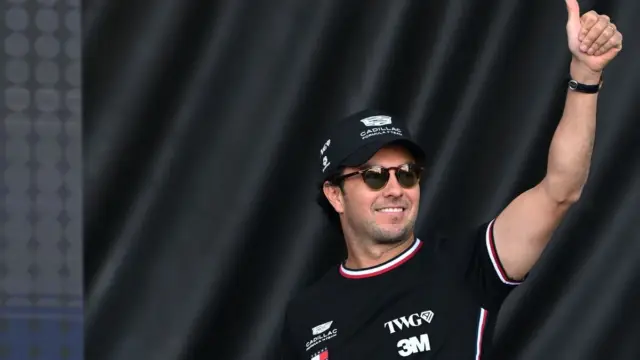 Sergio Pérez sorri ao lado de um carro de Fórmula 1 da equipe Cadillac